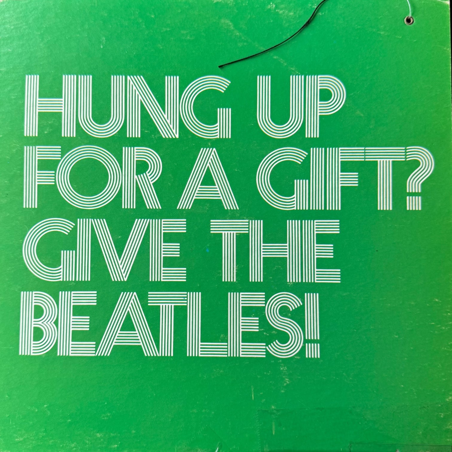Close-up of original Hung Up For A Gift Give The Beatles green header card with original black hanging wire intact from 1969 Capitol Records retail mobile